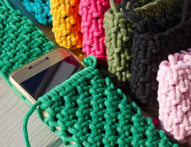 istock Small handbag for a mobile phone. Knitting macrame, pattern of multi-colored cotton cords. Handmade concept, hobby. 2148937627