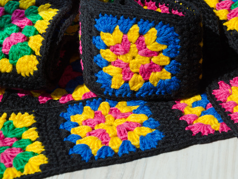 Colorful cotton granny square. Crochet texture close up photo. Knitted zigzag handmade jewelry.