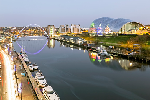 View across the river Tyne in the centre of Newcastle, UK.  Modern architecture can be seen and people can be seen on the promenade.