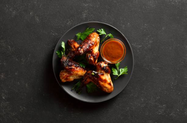 istock Bbq chicken wings on plate over dark stone background. Top view, flat lay 2148942468