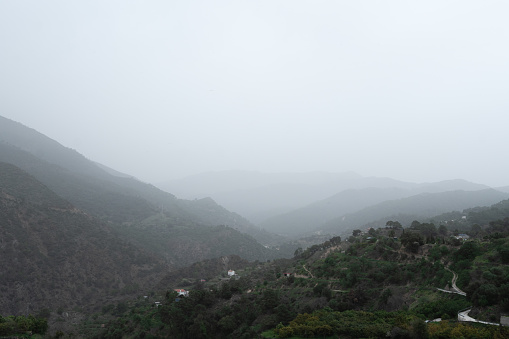 Istan, Spain, Andalusia - A winding road disappears into the fog-covered mountains, evoking a sense of mystery and travel in a remote landscape. High quality photo