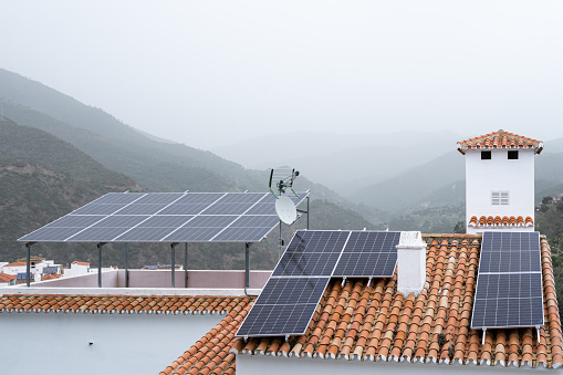 Sustainable living in a fog-covered mountain village, with solar panels on terracotta rooftops harnessing renewable energy. High quality photo