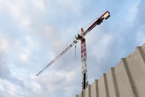 Construction crane with cloudy sky background.