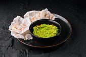 Fresh guacamole with rice chips on dark plate