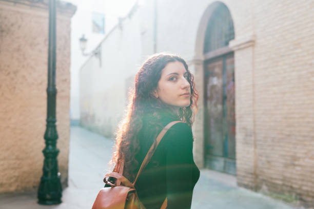 Tourist looking at camera while walking through the old town of a European city at sunset