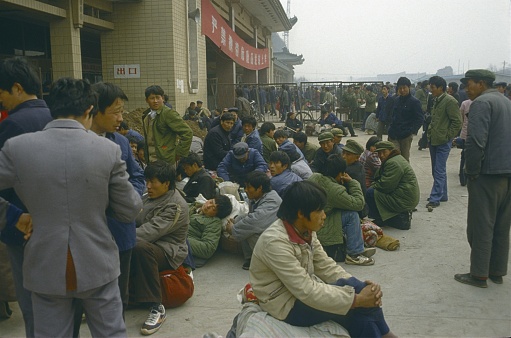 China (exact location not known), 1985. Chinese migrant workers in front of a train station building.