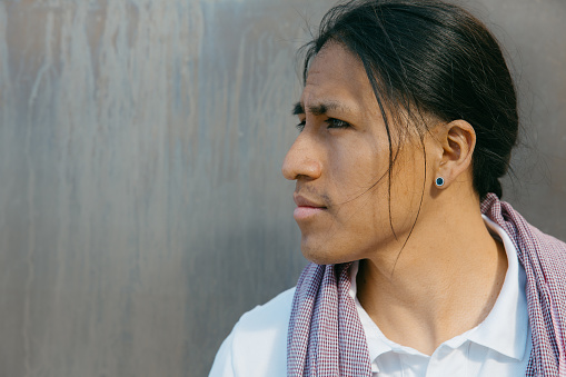 Close-up portrait of a thoughtful Ecuadorian young man with a titanium backdrop.