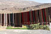 Abandoned village ruins of Riwaygh, in front view colorful carpets in Valley Necrosis, Oman