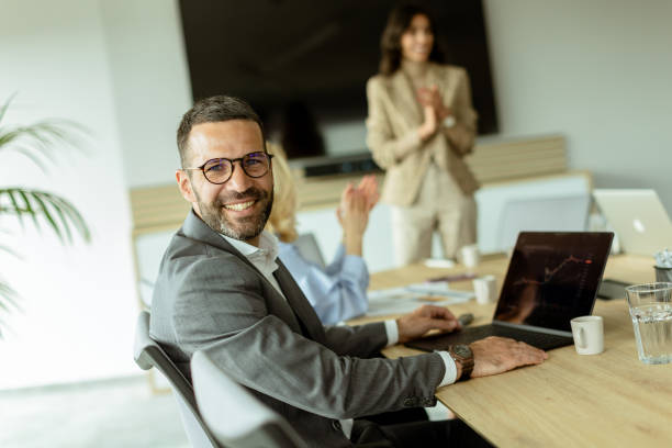 istock Smiling businessman in a modern office space enjoying a collaborative team meeting during work hours 2148948361