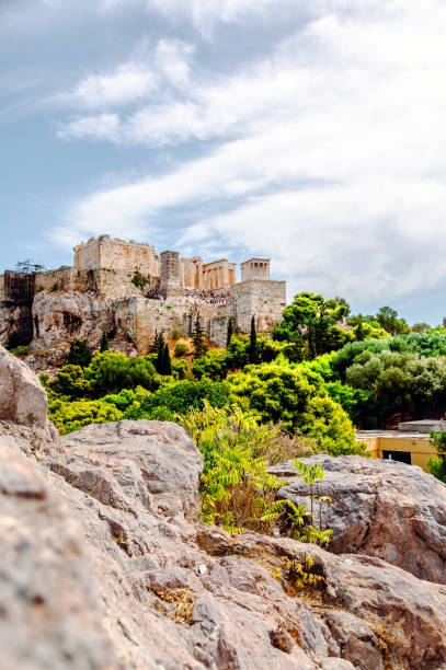 Behold the timeless majesty of the Acropolis, adorned with the Parthenon, Erechtheum, Beule Gate, and Temple of Athena, as viewed from the historic Areopagus Hill on rock in the heart of Athens. From this vantage point, ancient ruins tell stories of bygone civilizations against a backdrop of modern city life. The Parthenon stands as a symbol of classical architecture, while the Erechtheum's Caryatids captivate with their timeless grace. Beyond lies the Beule Gate and the Temple of Athena, each a testament to the city's rich cultural heritage. As the sun sets, casting a golden hue over the landscape, the Acropolis remains an enduring beacon of Athens' illustrious past.