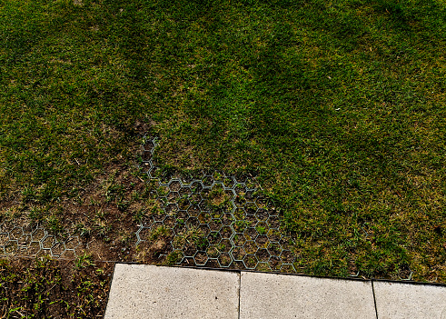 installation of a plastic mat as a substitute for lawn. plastic permeable tiles are filled with a fine putty. under the benches is a reinforced grass paving, permeability