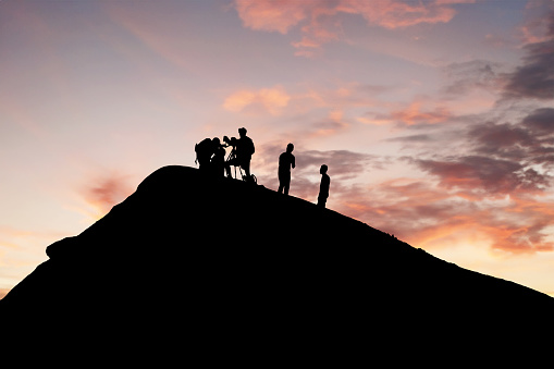 Silhouetted team conducting volcano research during picturesque sunset backdrop