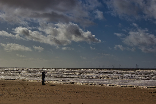 Lone silhouette of person photographing on sandy beach