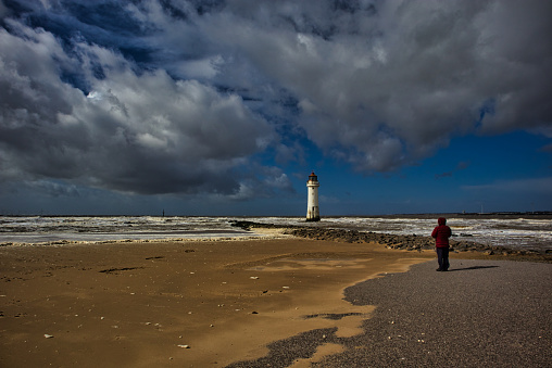 Perch Rock lighthouse tower with lone figure near beach