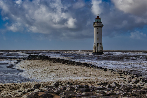 Perch Rock lighthouse tower with sea foam from rough seas