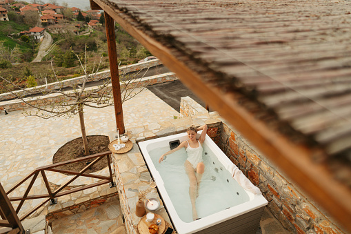 Photo of a young woman soaking in a hot tub hot tub, located on a slopes of a mountain village
