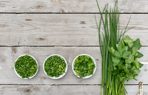 Bunch and sliced ​​fresh fresh parsley, chives and spring onion on a light wooden background