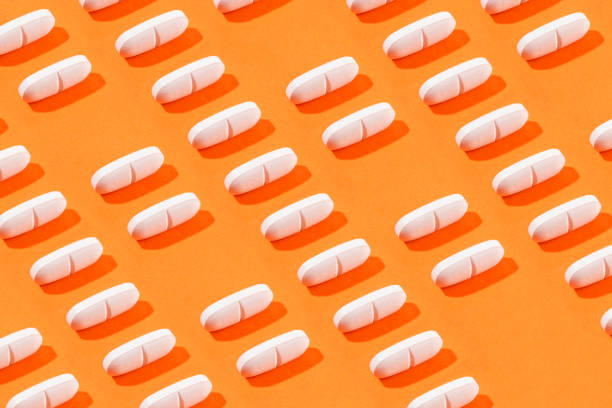 istock White Pills on Orange Colored Background 2148950985