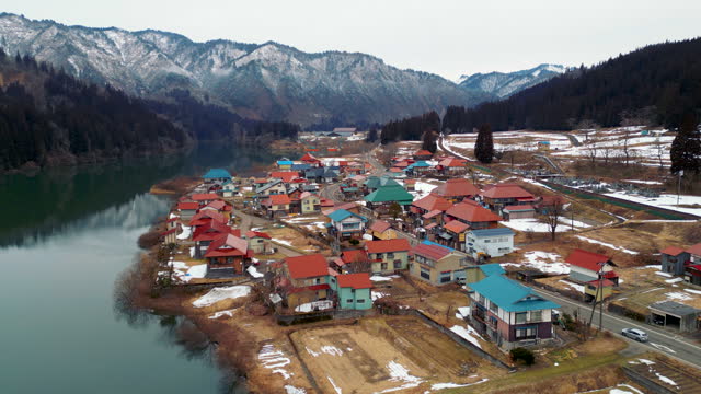 Aerial slide left village with reflection of snow mountain