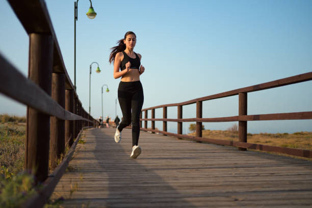 istock Young woman jogging on a wooden boardwalk at dusk 2148954190