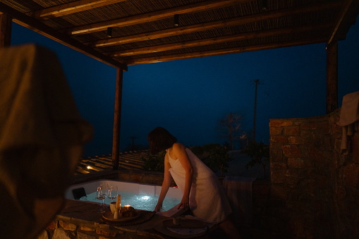 Photo of a young woman preparing a jacuzzi hot tub, located on a slopes of a mountain village