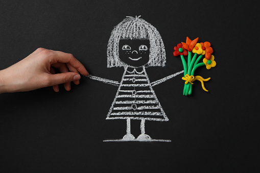 Chalk drawing, plasticine and female hand on blackboard