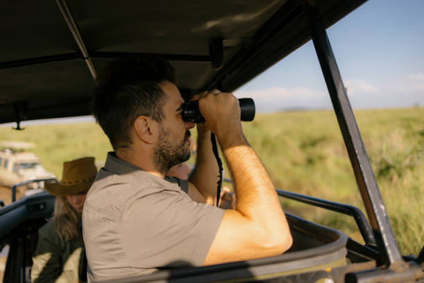 istock Carefree man exploring wildlife through binoculars from a jeep. 2148955370