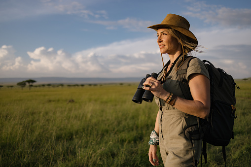 Happy female explorer enjoying in the wilderness of Masai Mara national reserve.