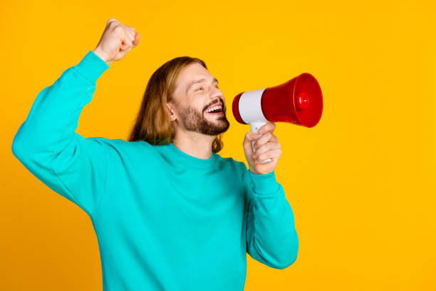 istock Profile portrait of delighted crazy man raise fist communicate loudspeaker empty space isolated on yellow color background 2148956476