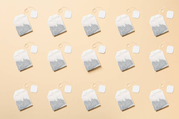 Putting tea bag into glass cup on white background, closeup