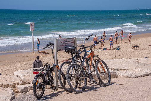 Tel Aviv, Israel - May 12, 2016:  Tel Aviv beaches crowded with people celebrating Independence Day. People walking and cycling on the beach, getting ready to watch air show in the sky.