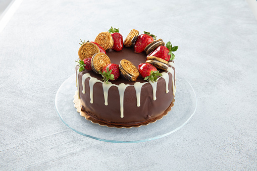 Chocolate cake with strawberries and biscuits on a white background.