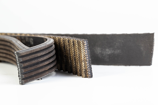 Torn timing belt and generator rivulet belt on a white background. Broken belts in the car, industry