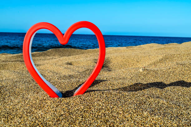 istock A red heart is on the sand next to the ocean 2148960181