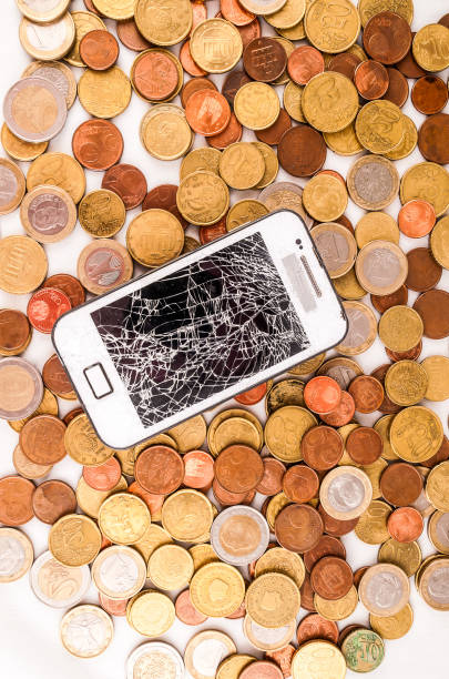 istock A broken cell phone is surrounded by a pile of coins 2148960413