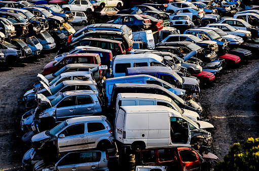 A lot of cars are piled up in a lot. The cars are old and rusted