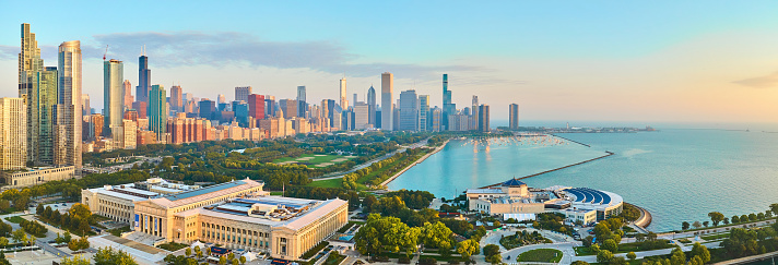 Aerial view of Chicago's skyline at golden hour, featuring the Field Museum, Lake Michigan shoreline, and verdant green spaces.