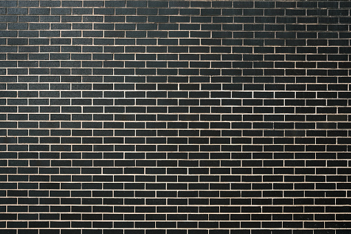 Section of a large clean black brick wall.