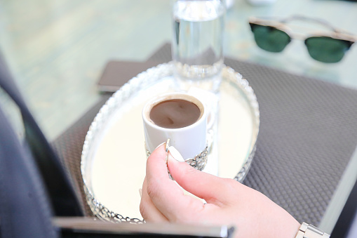 A person holding a cup of coffee balanced on a tray in their hand.