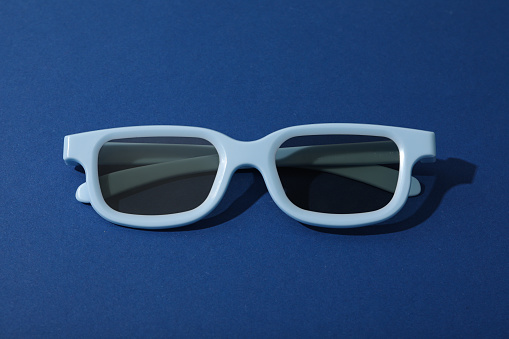 Light blue glasses with tinted lenses on dark blue background