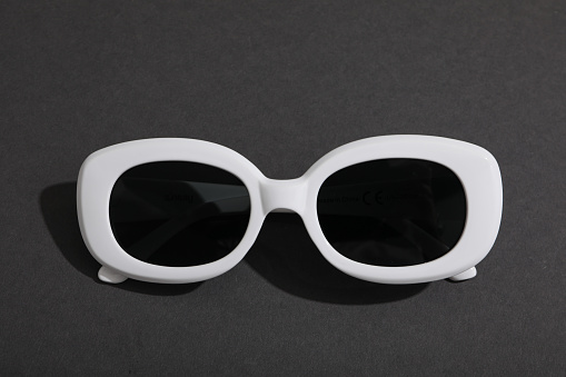 White glasses with dark lenses on dark gray background, close up