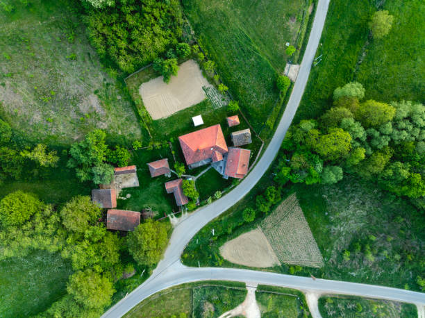 Idyllic aerial view of a country house with a yard, ancillary buildings and an orchard near country crossroads