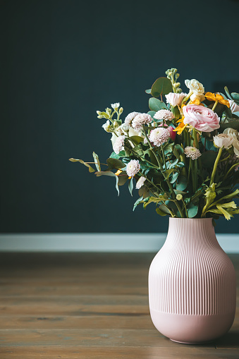 A stylish floral arrangement in a pink vase against a dark background, offering a chic and sophisticated aesthetic for interior styling. Concept: home decor and floral designs