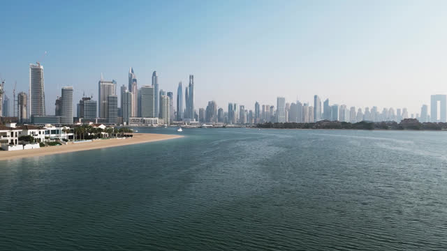 Drone flies over the sea overlooking Dubai and private villas
