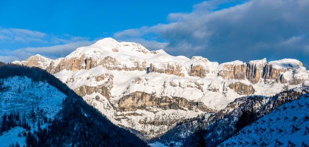 Dolomites in Italy. Sella mountain massif and mountain range at rising sun in March, covered with snow. Panoramic view from Pieve di Livinalogo near Arabba, famous ski and snowboard resort