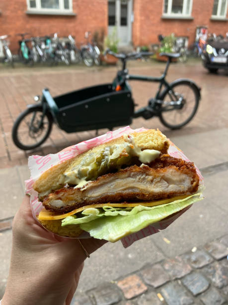 istock A Woman's Hand Holding a Chicken Burger with a Bicycle in the Background 2148967594