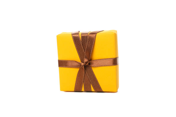 gift yellow box with gold ribbon bow close up isolated on white background