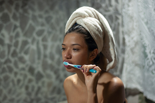 pretty slim latin woman Wrapped in a towel turban, a woman maintains her oral hygiene, with concentration and dedication.