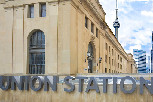 Union Station sign on Bay Street with Union Station exterior and the CN Tower in downtown Toronto Ontario
