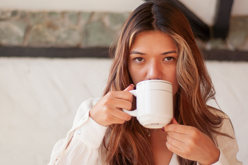 A woman enjoys a peaceful moment, holding a mug close, embodying tranquility with a soft gaze.